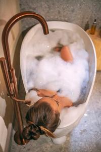 a girl is in a bath tub with a toilet at Leśny Chill House in Grodziec