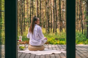 a woman sitting in a meditation position in the woods at Leśny Chill House in Grodziec