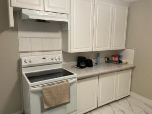 a white kitchen with white cabinets and an oven at Central Vally Private House in Abbotsford