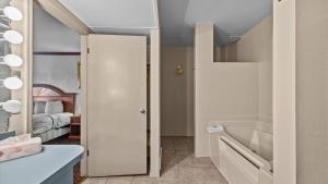 a room with a bathroom with a tub and a bedroom at Red Arrow Inn & Suites, a Travelodge by Wyndham in Montrose +19 photos