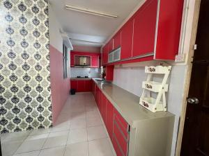 a red kitchen with red cabinets and a tile floor at Homestay Adelia SI in Seri Iskandar