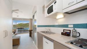 a kitchen with white cabinets and a view of the ocean at Breathtaking - Ettalong Beach Resort in Ettalong Beach