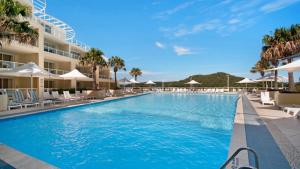 a pool at a resort with chairs and umbrellas at Breathtaking - Ettalong Beach Resort in Ettalong Beach