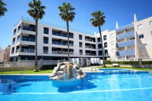 a swimming pool in front of a building with palm trees at AL045 Pinada Beach III La Mata in La Mata
