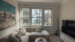 a living room with a couch and a large window at Manly Waterfront Apartment Harbourside in Sydney