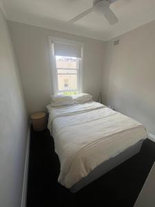 a white bedroom with a bed with a window at Manly Waterfront Apartment Harbourside in Sydney