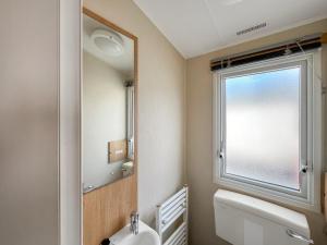 a bathroom with a mirror and a toilet and a window at Peppy in Newton Stewart +1 photo