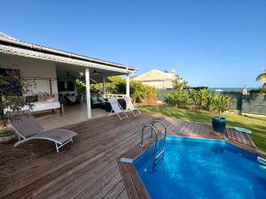 a swimming pool on a wooden deck next to a house at Villa Eli -6pers- piscine in Petit-Bourg