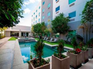 a hotel courtyard with a swimming pool and trees at Hotel Mirra San Luis in San Luis Río Colorado