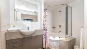 a bathroom with a sink and a mirror and a tub at Pool Delight - Ettalong Beach Resort in Ettalong Beach