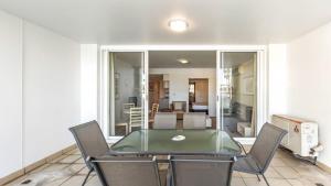 a dining room with a glass table and chairs at Pool Delight - Ettalong Beach Resort in Ettalong Beach