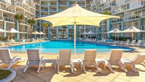 a group of chairs and an umbrella next to a pool at Pool Delight - Ettalong Beach Resort in Ettalong Beach +14 photos