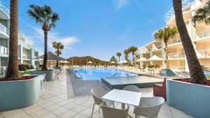 a pool at the resort with palm trees and tables and chairs at Pool Delight - Ettalong Beach Resort in Ettalong Beach