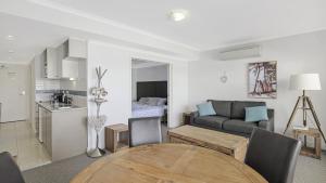 a living room with a couch and a table at Poolside Paradise Ettalong Beach Resort in Ettalong Beach