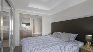 a bedroom with a large bed and a bathroom at Poolside Paradise Ettalong Beach Resort in Ettalong Beach