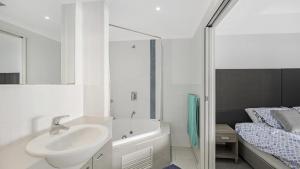 a bathroom with a sink and a tub and a bed at Poolside Paradise Ettalong Beach Resort in Ettalong Beach