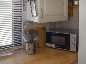 a kitchen with a microwave and a table with utensils at Angie's Beachside House in Saint Osyth +15 photos