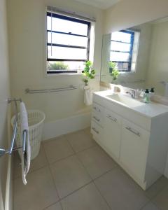 a white bathroom with a sink and a mirror at 2-Bedroom Townhouse Next to the Hospital in Bendigo +34 photos