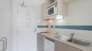 a kitchen with a sink and a microwave at Seashells - Ettalong Beach Resort in Ettalong Beach