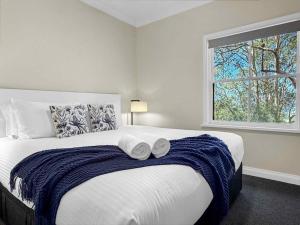 a bedroom with a large bed with two towels on it at Villa Remana in Pokolbin