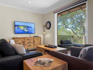 a living room with two couches and a tv at Villa Remana in Pokolbin