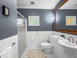 a bathroom with a sink and a toilet and a mirror at Villa Remana in Pokolbin