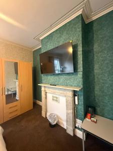 a room with green walls with a fireplace and a mirror at Near city centre, Derby train station and royal Derby hospital in Derby