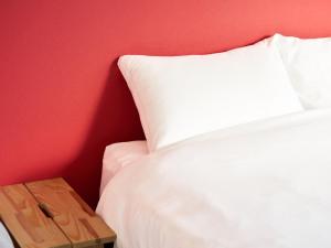 a bedroom with a white bed and a red wall at マーケットステイ新宮 in Shingū