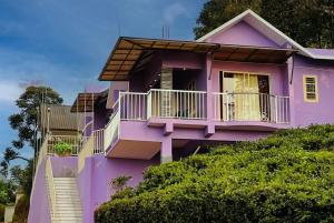 a pink house with a balcony on a hill at Aikara cottages in Vagamon