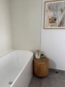 a bathroom with a bath tub and a picture of a cow at McNeil Luxury Studio in Wanaka +7 photos
