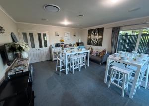a dining room with white tables and stools at Waitomo Orchard Estate B&B in Otorohanga