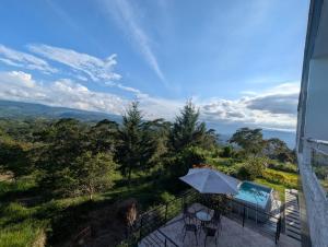 a balcony with a table and an umbrella and a pool at Hotel Campestre El Alcazar in Moniquirá +24 photos