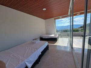 a bedroom with two beds and a large window at Hotel Campestre El Alcazar in Moniquirá