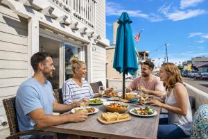 a group of people sitting at a table eating food at Beach Escape with Patio! 2 Min Walk to Sand & Surf in Newport Beach