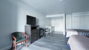 a room with two beds and a television and a desk at Ocean Breeze Inn in Saint Augustine Beach