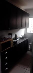 a kitchen with black cabinets and a microwave on a counter at Casa condomínio in Maceió +2 photos