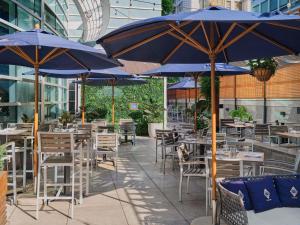eine Terrasse mit Tischen und Stühlen unter blauen Sonnenschirmen in der Unterkunft Sofitel Montreal Golden Mile in Montreal