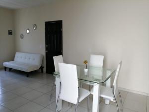 a dining room with a glass table and white chairs at VENECIA APARTMENT, Excellent Location in Tepic