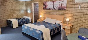 a room with two beds in a brick wall at Macintyre Motor Inn in Goondiwindi