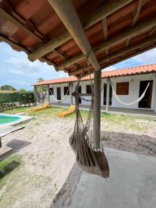 a hammock hanging from a porch of a house at Suite Adam 3 em Caraíva com piscina 900m da Vila in Caraíva