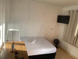 a bedroom with a bed and a desk with a lamp at Suítes Goiabal in Pirenópolis