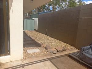 a side yard with a brick wall and rocks at Peaceful and private two bedroom unit in Alice Springs