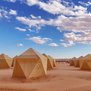 a row of tents in the desert under a cloudy sky at Camp ainelseid in Kebili