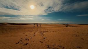 two people walking in the sand in the desert at Camp ainelseid in Kebili