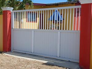 a white gate with an umbrella on a house at Sunny Isle Apartment in Rooi Master