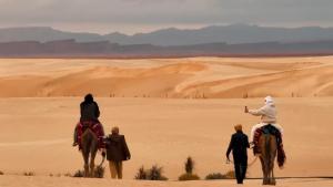 a group of people riding horses in the desert at Camp ainelseid in Kebili