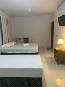a hotel room with two beds and a night stand at Suítes Goiabal in Pirenópolis +27 photos