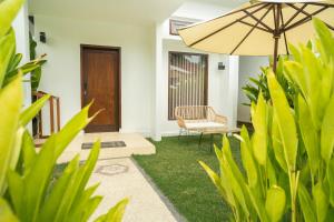 a patio with a chair and an umbrella and grass at Nomada Villas - Giant Pool - Private Kitchen - Free Gym Access - Up to 40Mbps WiFi in Kuta Lombok