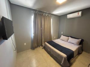 a bedroom with a bed and a television in it at Búzios Family House in Búzios