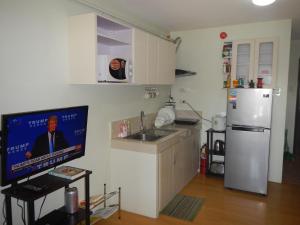 eine Küche mit einem TV, einer Spüle und einem Kühlschrank in der Unterkunft One Oasis Condotel in Davao City